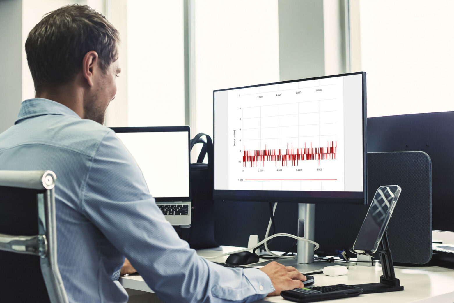 Empleado en la oficina comprobando datos de medición en su ordenador